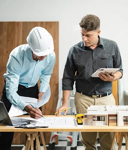 Contractor meeting with a client at a kitchen table reviewing renovation assessment forms