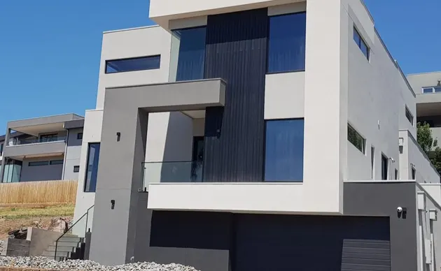 Completed custom home exterior with fresh siding, large windows, and attached garage