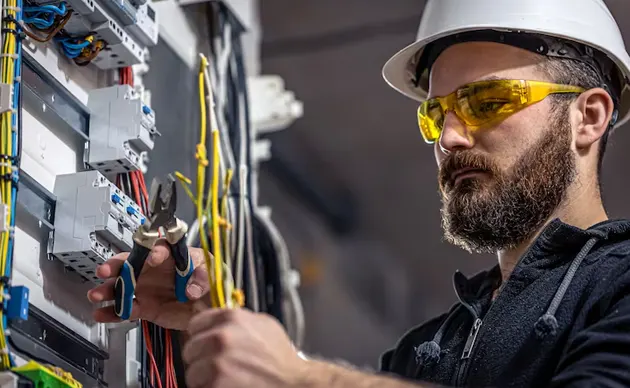 Electrician installing wires inside an open wall panel on a residential project