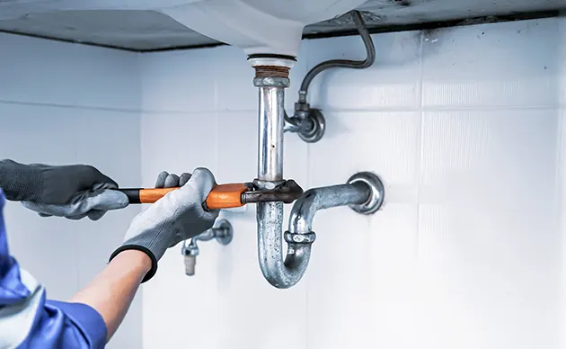 Technician soldering copper water pipes in an unfinished basement utility area