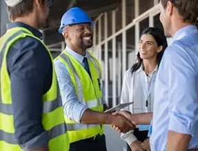 Estimator presenting a detailed construction quote beside architectural drawings on a conference table