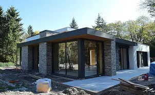 Architect and couple examining custom home blueprints spread across a large drafting table