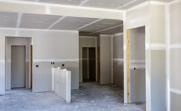 Contractor applying joint compound to drywall seams in a remodeled room