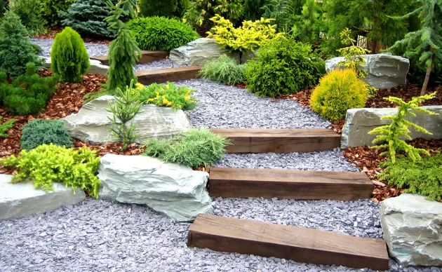 Landscaper positioning shrubs and mulch around a suburban front yard walkway